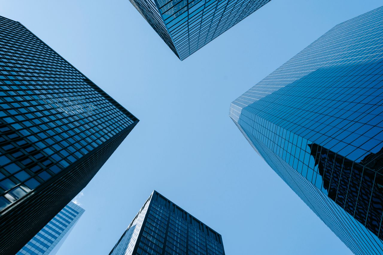 our-experience Low angle of high business towers with glass mirrored windows located in megalopolis downtown against blue sky